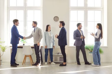 Bir grup kendine güvenen iş adamı erkek ve kadın bir toplantı sırasında ofiste konuşuyor. Şirket çalışanları içeride çalışıyor, iş ve iş projelerini tartışıyor. Takım çalışması konsepti.