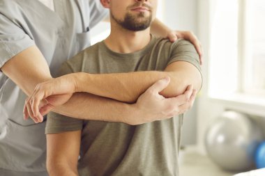 Beyaz adamın koluyla rehabilitasyon hastanesinde çalışan profesyonel bir kayropraktik uzmanı ya da fizyoterapistin kesilmiş fotoğrafı. Fizyoterapi ve osteopatik tıp konsepti.