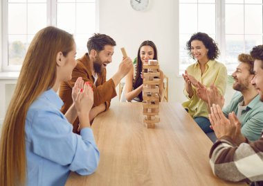 Bir grup mutlu arkadaş oyun oynuyor ve birlikte eğleniyorlar. Bir kaç neşeli genç evdeki masada oturuyor ve kuleden ahşap bloklar çıkarıyor.