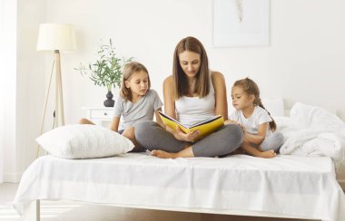 Genç anne, küçük çocuklarıyla yatakta oturup onlara masal okuyor. Anne şefkati, kitap tutmak, evde iki çocukla hikaye anlatmanın tadını çıkarmak. Mutlu aile birlikte vakit geçiriyor..