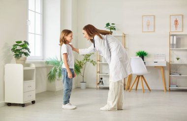 Pediyatrist doktor, çocuğun refahı ve konforu için sağlık desteği, profesyonel yardım ve dostça diyalog sunan bir hasta çocuğa hastanede yardım eder..