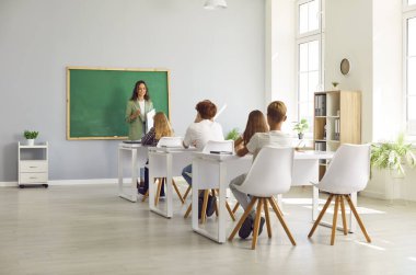 Okul sınıfındaki bir grup öğrenciye ders veren profesyonel bayan öğretmen. Çocuklar ve öğrenciler öğretmenlerinin rehberliğinde birlikte öğrenme ve öğrenme ile meşguller..