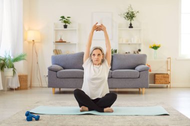 Yogi, yaşlı sportif, son sınıf öğrencisi, kollarını esnetme, yoga, oturma egzersizi, rahatlama pozisyonu, paspas, zemin üzerinde çalışma, sağlık, denge, bakım için günlük spor kıyafetleri giyme.