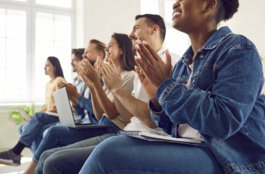 Ders ya da seminer sırasında alkışlayan çeşitli öğrenci ve işçi toplulukları tatmin oldu. Kot giymiş, sıradan giyinmiş, dizüstü bilgisayarlı ve dizüstü bilgisayarlı sandalyelerde oturan çok ırklı insanların kırpılmış görüntüsü..