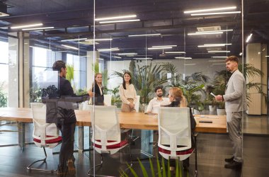 Patron, çalışanlar ve işadamları ekibiyle ofiste bir iş görüşmesi yapıyor. Mesleki görevleri tartışmak, takım çalışmasını teşvik etmek ve grubu ortak hedeflere yönlendirmek.