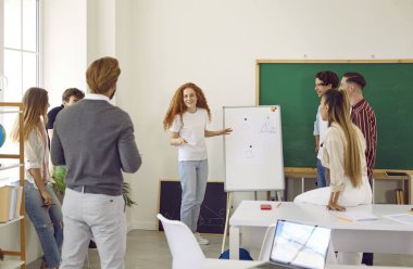 Takım sınıf arkadaşlarının raporlarını dinler, bu da araştırma istatistiklerini beyaz tahtada tablolar ve grafikler şeklinde gösterir. Öğretmen ve öğrenci grubu, kız raporlarının tartışılmasına katıldılar.
