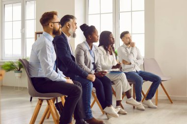 Çeşitli iş adamlarından oluşan bir grup sandalyede oturup meslektaşlarını ya da iş yerindeki liderlerini dinliyorlar. Şirket çalışanları iş projesini tartışıyorlar.