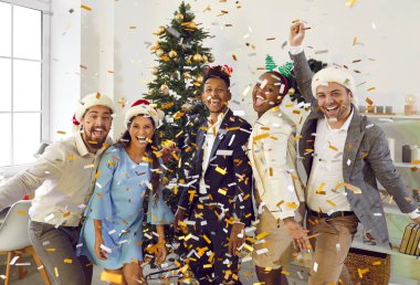 Şirket partisi. Bir grup pozitif ve arkadaş canlısı iş arkadaşı, ofisteki yeni yıl partisinde eğleniyor, gülüyor ve konfeti atıyorlar. Neşeli çok ırklı iş arkadaşları yüksek sesle gülüyorlar..