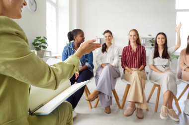 Bir grup farklı kadın profesyonel bir işletme koçuyla tanışıp iletişim kuruyor. Bir ofiste oturmuş, fikirleri tartışıp sorular soran mutlu genç bayanlardan oluşan bir takım.