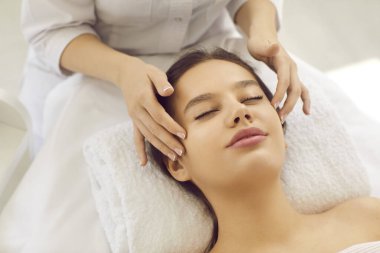 Kozmetik uzmanının kapanışı güzellik salonundaki kadın müşteriye yüz masajı yapıyor. Cilt bakımı uzmanı, kadın hastalar için cilt bakımı prosedürü uyguluyor. Kozmetoloji kavramı.