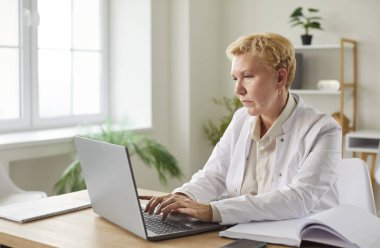 Üst düzey doktor, beyaz üniformalı ciddi bir kadın doktora odaklanmıştı. İnternette çalışıyordu. Laptop bilgisayarında çalışıyordu.