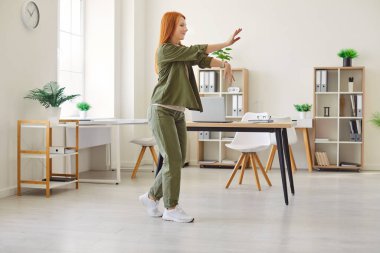 Müzik eşliğinde dans eden mutlu bir kadın, ofiste hoplayıp zıplayan, başarılı bir başarıyı kutlayan. Profesyonel bir iş ortamında iş başarılarının keyfini çıkarırken eğlence, eğlence ve heyecan.