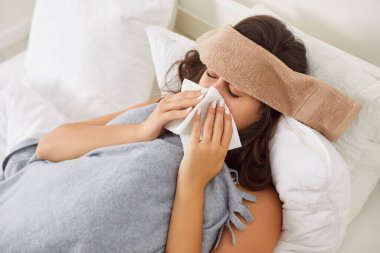 Hasta, genç bir kadın, ekose kumaşa sarılmış, başında ıslak havluyla yatakta yatıyor, ateşi var, mendile hapşırıyor. Soğuk, mevsimsel enfeksiyon ya da grip virüsü taşıyan mutsuz bir kız yorgun ve sağlıksız hissediyor..