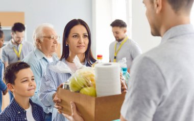 Bir anne ve çocuk, bir gönüllüden bir kutu yiyecek alır, yakın plan. Mültecilere yardım kavramı, hayır kurumunun çalışması, yoksul ülkelerin ailelerine destek