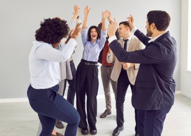 Genç, mutlu iş adamları ve takım elbiseli şirket çalışanları iş hayatında başarıyı kutlarken ya da ofiste iyi bir anlaşma yaparken eğleniyorlar. Takım çalışması ve takım oluşturma kavramı.
