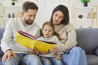 Aile hayali maceralarla birleştirilir. Çocuklu genç bir aile, peri masalları okumaya dalmış, birlikte kanepede oturuyor. Anne, baba ve küçük kız sırıtarak sarı kapaklı kitaba bakıyorlar..
