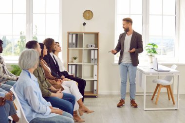 Ofisteki bir iş toplantısında konuşan genç bir iş adamı çeşitli şirket çalışanlarının önünde ya da bir grup personelin sırayla koltuklarda oturup liderlerini dinlediği bir toplantıda..