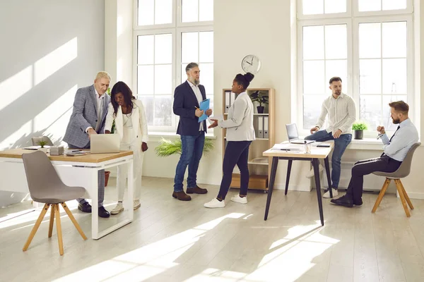 Bir grup iş adamının toplantıdan sonra konuştuğu uzun bir fotoğraf. Şirket çalışanları ekibi ya da grup çalışanları, ara sırasında ofiste birbirleriyle konuşuyorlar..