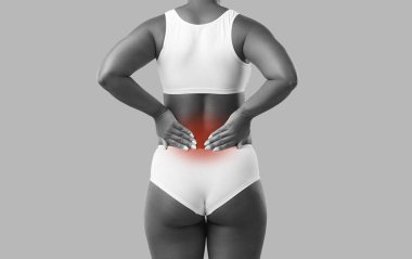 Arka planda duran beyaz iç çamaşırlı ve ellerini sırtında tutan kadının dikiz görüntüsü. Sırt veya böbrek ağrısından muzdarip bir kadının görüntüsü. Acı veren bölge kırmızıyla işaretlenmiş.