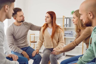 Çeşitli gençler grup psikoterapi seansı sırasında bir çember içinde oturuyorlar. Psikolog açık tartışmaları kolaylaştırıyor, toplum hissini ve karşılıklı desteği teşvik ediyor..