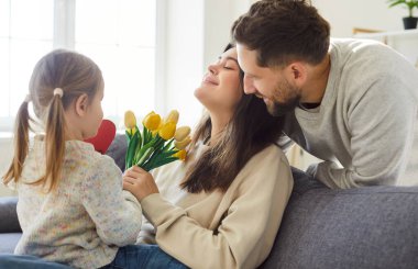 Sevgi dolu baba ve küçük kız annelerine bir buket çiçek hediye eder. Tatili evde kutlarken, özel bir gün için sevgi ve minnettarlıklarını ifade ederler..
