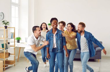 Neşeli farklı arkadaşlar birlikte eğleniyorlar. Heyecanlı bir grup insan büyük başarıları için arkadaşlarını tebrik ediyor. Mutlu Afrikalı genç Amerikalı kadın dostlarından sarıldı ve tebrik etti.