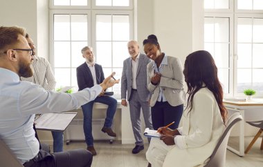Bir grup iş adamı toplanıp ofiste bir toplantıda iş ve iş projelerini tartışıyorlar. Şirket çalışanları sohbet ediyor ve gülüyor. Harika kararlar veriyorlar..