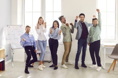 Mutlu iş adamları başarıyı kutluyor. Bir grup neşeli, heyecanlı genç insan ofiste bir iş toplantısında eğleniyorlar. Takım çalışması ve başarı kavramları