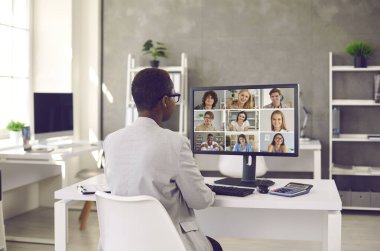 Uzaktan kumandalı meslektaşların tele-iş ekibiyle çalışan siyahi iş kadını. Arka plan kadın denetçisi ya da vergi danışmanı, bir grup mutlu genç girişimciyle birlikte ofis masasında oturuyor.