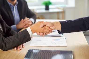 Profesyonel bir ofis toplantısı sırasında el sıkışan iş adamlarının yakınlaşması bir anlaşma ve ortaklık anlamına gelir. Bir şirket ortamında topluluk, anlaşma ve takım çalışması.