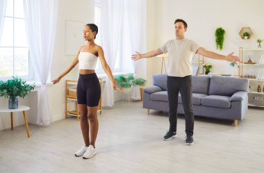 Evde birkaç yoga egzersizi, birlikte antrenman yapan mutlu aktif insanlar. Genç, zinde bir kadın ve erkek dengeli bir şekilde nefes alıyor. Takım ruhu, günlük sağlıklı aile rutini.