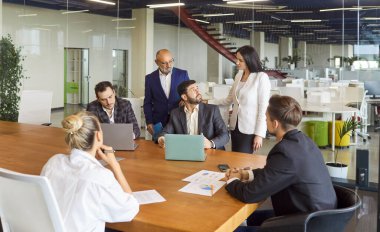 Profesyonel ofis çalışanlarının iş toplantısı finans projesi tartışması, problemleri çözmek için. Masada dizüstü bilgisayarlarla oturan bir grup insan iş arkadaşlarıyla brifing hakkında tartışıyor.
