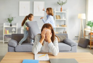 Yorgun anne, çocuklarına kötü davranarak ve gürültü çıkararak, kaosu, stresi ve aile ve iş sorumluluklarını dengeleme mücadelesini resmederken, evden çalışmaya çalışıyor..