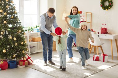Mutlu birleşik aile dansları süslü Noel ağacının yanında, birlikte neşeli havanın tadını çıkarıyoruz. Neşeli ebeveynler ve çocuklar Noel tatillerinde evde eğleniyorlar. Mutlu Noeller, mutlu yıllar..