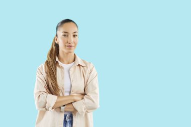 Kendine güvenen, kollarını çapraz bağlamış, mavi stüdyo arka planında izole edilmiş, fotokopi çeken ve kameraya neşeli bakan beyaz bir kadının portresi..