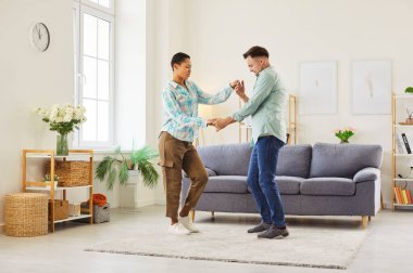 Genç çift evde dans ediyor. Oturma odasında el ele tutuşan ve dans eden mutlu aile çifti, rahatlama zamanlarında ilişkileri artarken aşkı, eğlenceyi ve mutluluğu paylaşıyorlar.