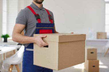 Erkek taşıyıcı ya da üniformalı taşıyıcı karton kutuyu tutarak müşteriye taşınmasında ya da taşınmasında yardımcı olur. Teslimatçı nakliye ya da nakliye şirketinden. Müşteri eşyalarını yükler ya da indirir..