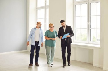 Emlakçı, alıcılar boş bir daireye girerken pano evraklarını inceliyor. Emlakçı yaşlılara parlak bir ev gösteriyor ve bir gezi sırasında kontratı tartışıyorlar..