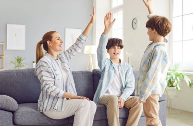 Mutlu aile, anne ve oğullar, evde beşlik çakın. Aile içinde mutluluk ve güçlü bir bağ, ebeveynliğin ve yakın ebeveyn ilişkisinin neşesini gösteriyor..