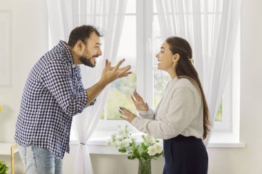 Kızgın çiftin ilişki anlaşmazlığı, evde insanların öfke ve stresle bağırışması. Erkek ve kadın pencerenin önünde tartışır, kötü sözler söyler ve kötü iletişim ve stres göstermek için jest yaparlar.