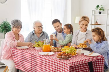 Aile yemek masasında birlikte oturur, yemek yer ve evde yemek yer. Mutlu buluşmalar sohbet ve boş zamanlarla doludur. Yemek yemenin ve tatilde vakit geçirmenin mutluluğunu kutlarlar..