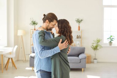 Mutlu çift evde yüz yüze duruyor ve birbirlerinin gözlerinin içine bakarken nazikçe alınlarına dokunuyor. Romantik erkek ve kadın sarılıyor, öpüşüyor ve samimi bir anı paylaşıyorlar..