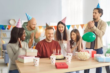 Neşeli çoklu etnik arkadaş grubumuzun doğum günü partisi kutlu olsun. Çeşitli insanlar gülümsüyor. Arkadaşlarından doğum günü hediyesi alıyor, eğleniyor, eğleniyor.