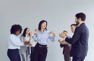 Bir grup mutlu iş adamı takım elbiseli kadın ve erkekler ofiste eğleniyor. Genç gülümseyen şirket çalışanları başarıyı kutluyor..