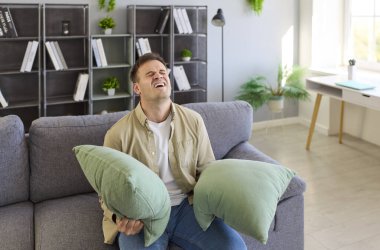 Evdeki kanepede yastık bloklayan sinirli adam. Oturma odasında yastıkları kulaklarına bastırıp, yumruklardan kurtulmak isterken hayal kırıklığı gösteriyor. Komşu gürültüsü stresi.