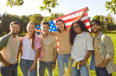Amerikan bayrağını tutan mutlu insanların portresi, dışarıda bağımsızlık gününü kutlamak, tatil ruhunu onurlandırmak, grup neşe içinde bir araya gelmek, vatanseverlik olaylarını açık bir alanda coşkuyla işaretlemek..