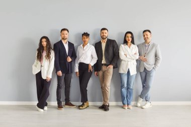 Ofis duvarında duran ciddi iş adamları grubu, kendine güvenen farklı takımların portresi. Girişimciler ve uzmanlar birlikte poz veriyorlar. Profesyonellerin işbirliği, kurumsal disiplin kavramı