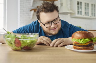 Hamburgeri salataya tercih eden aç bir adam. Mutfakta komik kilolu birini diyet olarak seçiyor. Hamburger yemek isteyen tombul adam, sağlıklı ve sağlıksız yiyecekleri karşılaştır.