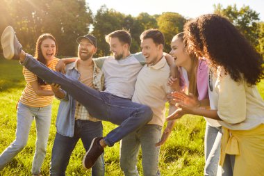 Şehir parkında parti sırasında eğlenen ve gülen mutlu arkadaş kalabalığı, eğlence dolu bir parıltıyı açık havada mutluluk ve grup şenliği ile harmanladı..