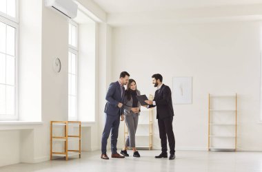 Erkek emlakçı, ofis odası satın almak isteyen, sözleşmenin şartlarını tartışmak, satın alma seçeneklerini araştırmak, kiralamanın faydalarından bahsetmek isteyen iş çiftiyle görüşüyor..